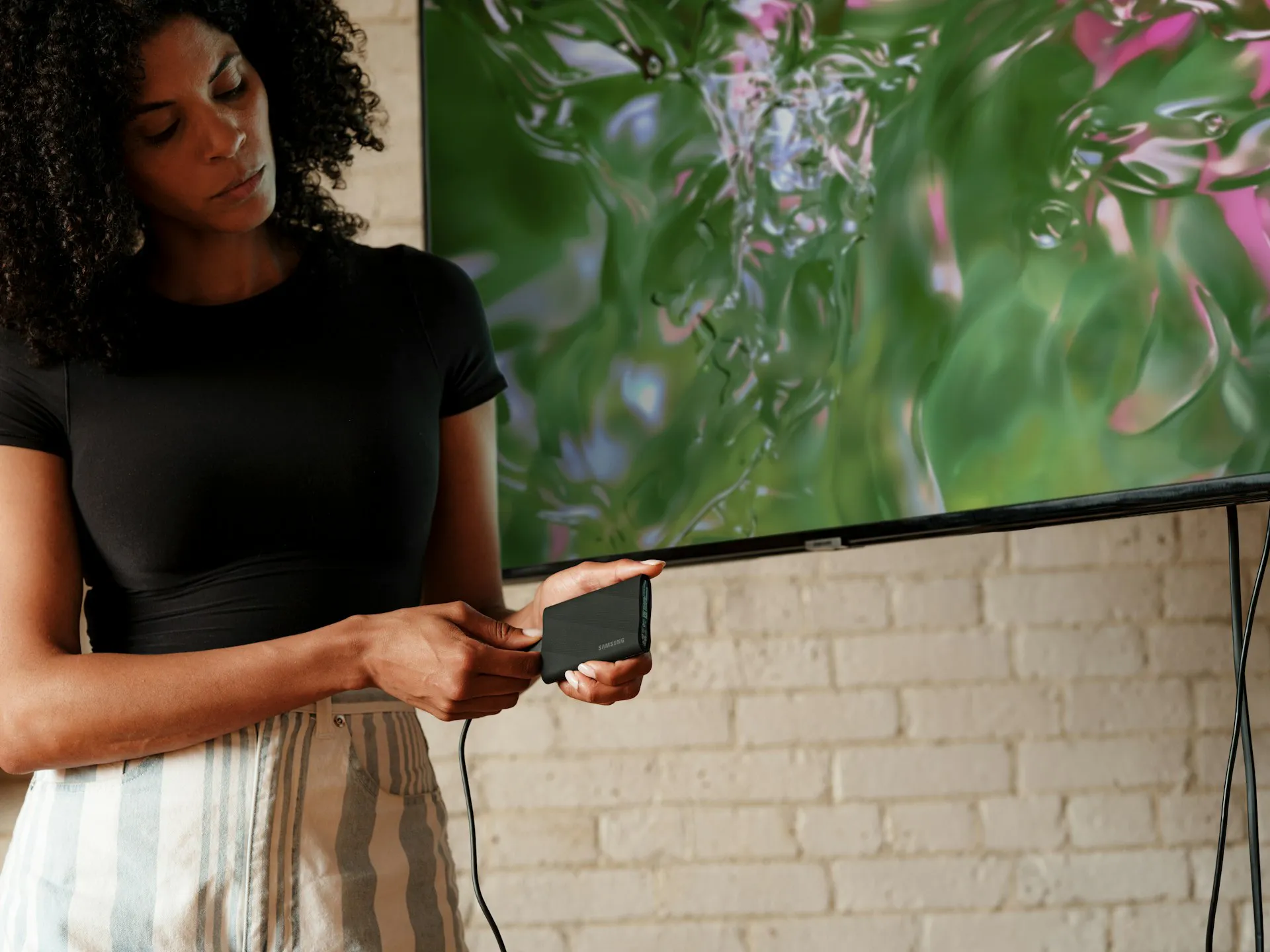 Mujer conectando un disco duro externo a un televisor